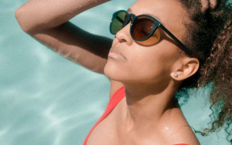 woman wearing sunglasses stands in a pool and basks in the sun