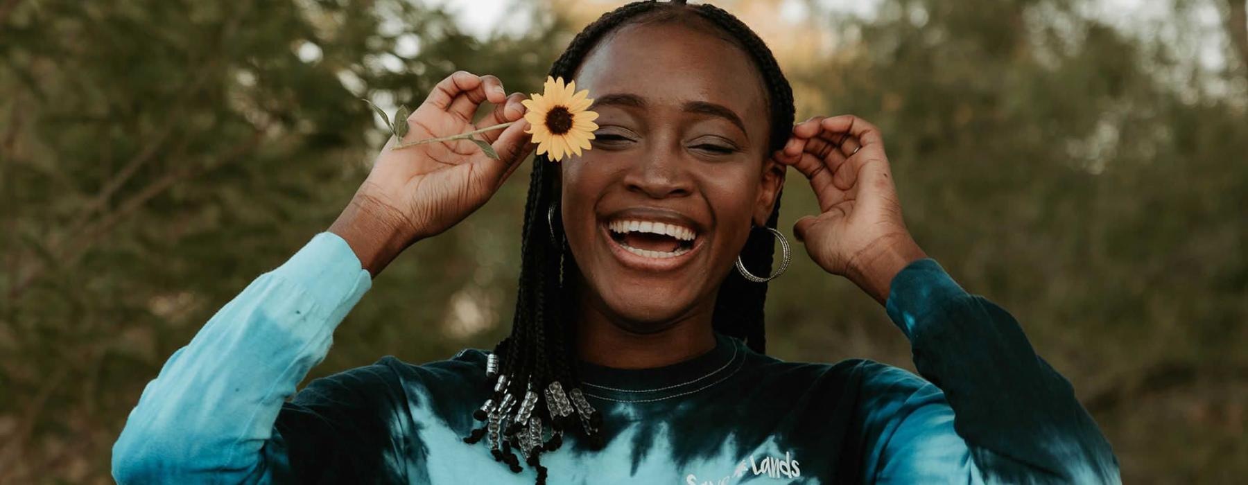 woman holds a flower in her hair in a park